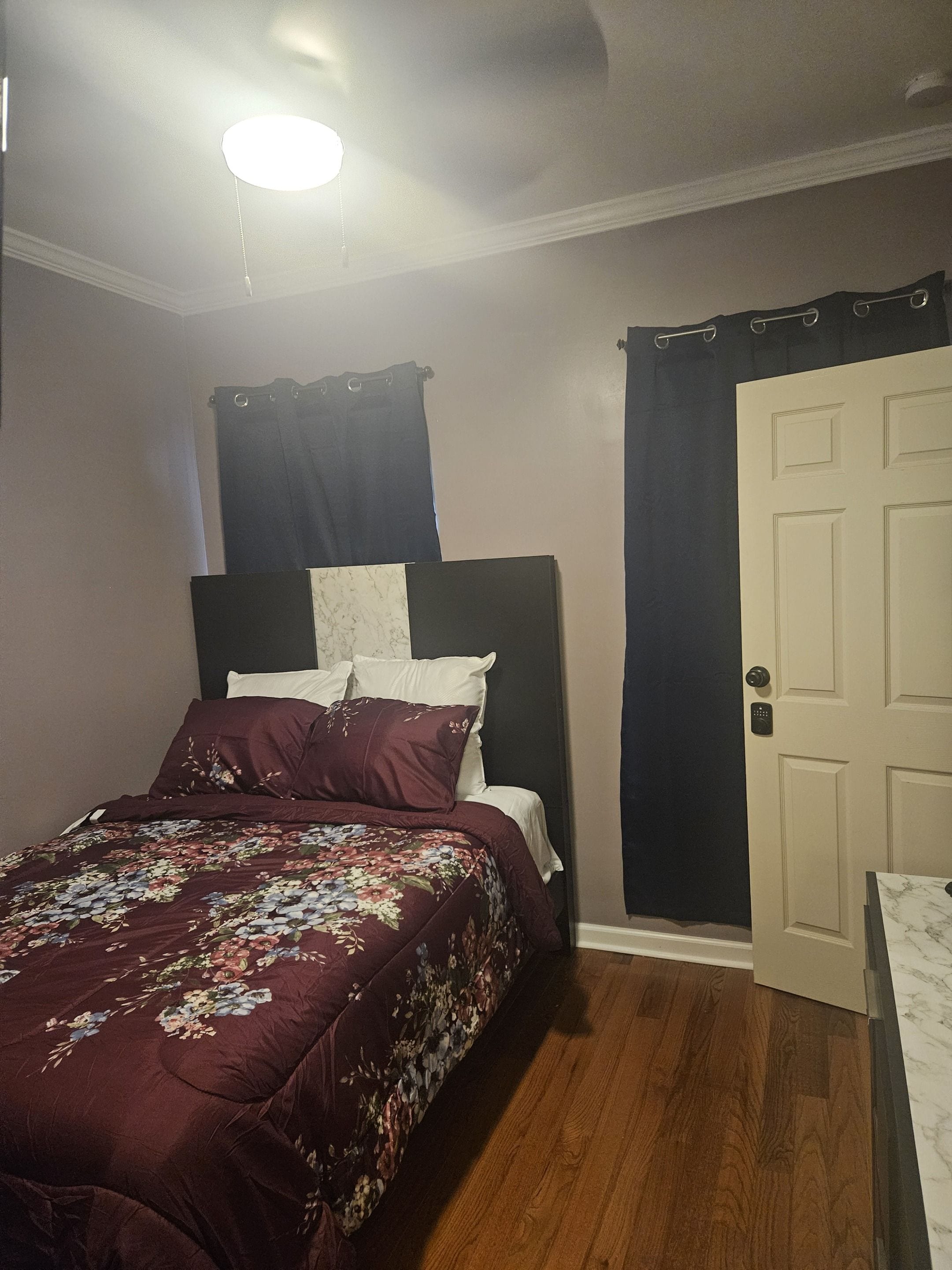 A bedroom with a bed, a door, and a ceiling light.
