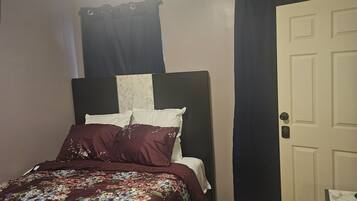 A bedroom with a bed, a door, and a ceiling light.