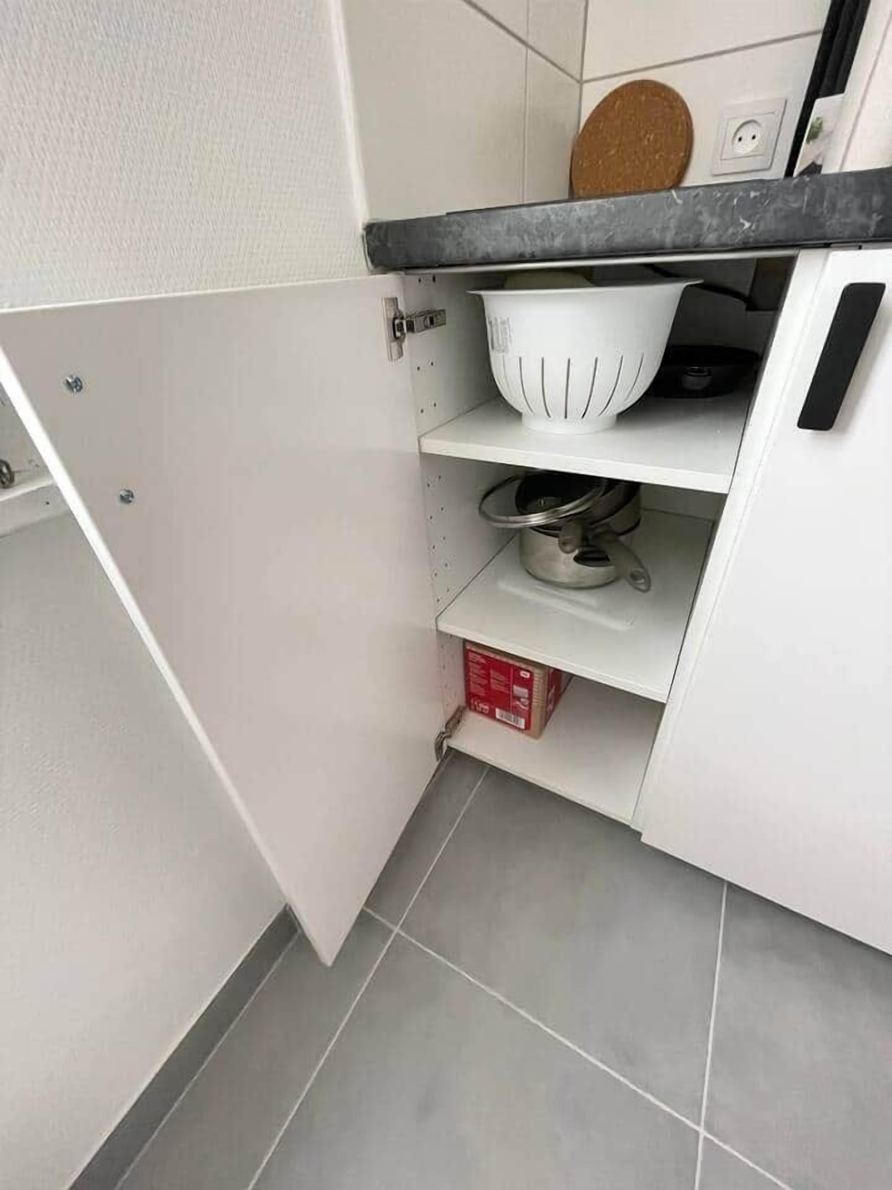 Eine Küche mit weißen Schränken, einer schwarzen Arbeitsplatte und einer roten Kiste auf der unteren Ablagefläche.