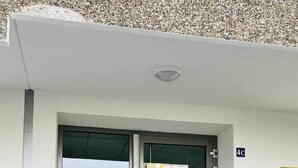 A modern building entrance with a glass door, a small outdoor area with steps, and a sign indicating the unit number 4C.