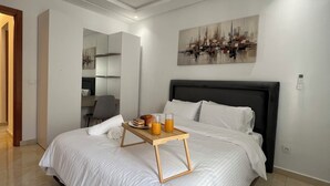 A modern bedroom with a bed, bedside table, and a painting on the wall. - Stylish & Cozy | Downtown 2BR Netflix+Fast Wifi•AC (rabat)
