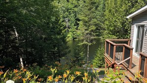 Una terraza de madera con vistas a un lago rodeado de bosque denso.