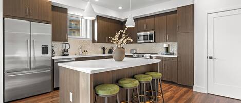 A modern kitchen with a central island, stainless steel appliances, and wooden cabinets.