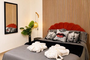 A bed with a red headboard, two pillows with a face design, a bedside lamp, and a mirror on the wall. - MSuite Etna Sicily – Elegant Apartment with Private Terrace between Etna, Taormina & Sea (Macchia)