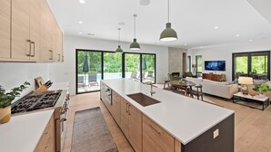 A modern kitchen with a large island, wooden cabinets, and pendant lighting. - Blackwood Shores - 6 bed, pool, hot tub, game room (Lakeside)