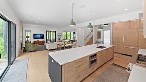 A modern kitchen with a central island, wooden cabinets, and pendant lighting. - Blackwood Shores - 6 bed, pool, hot tub, game room (Lakeside)