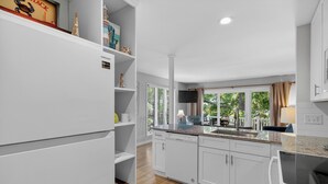 Une cuisine moderne avec des meubles blancs, un plan de travail en granit et un lave-vaisselle encastré.