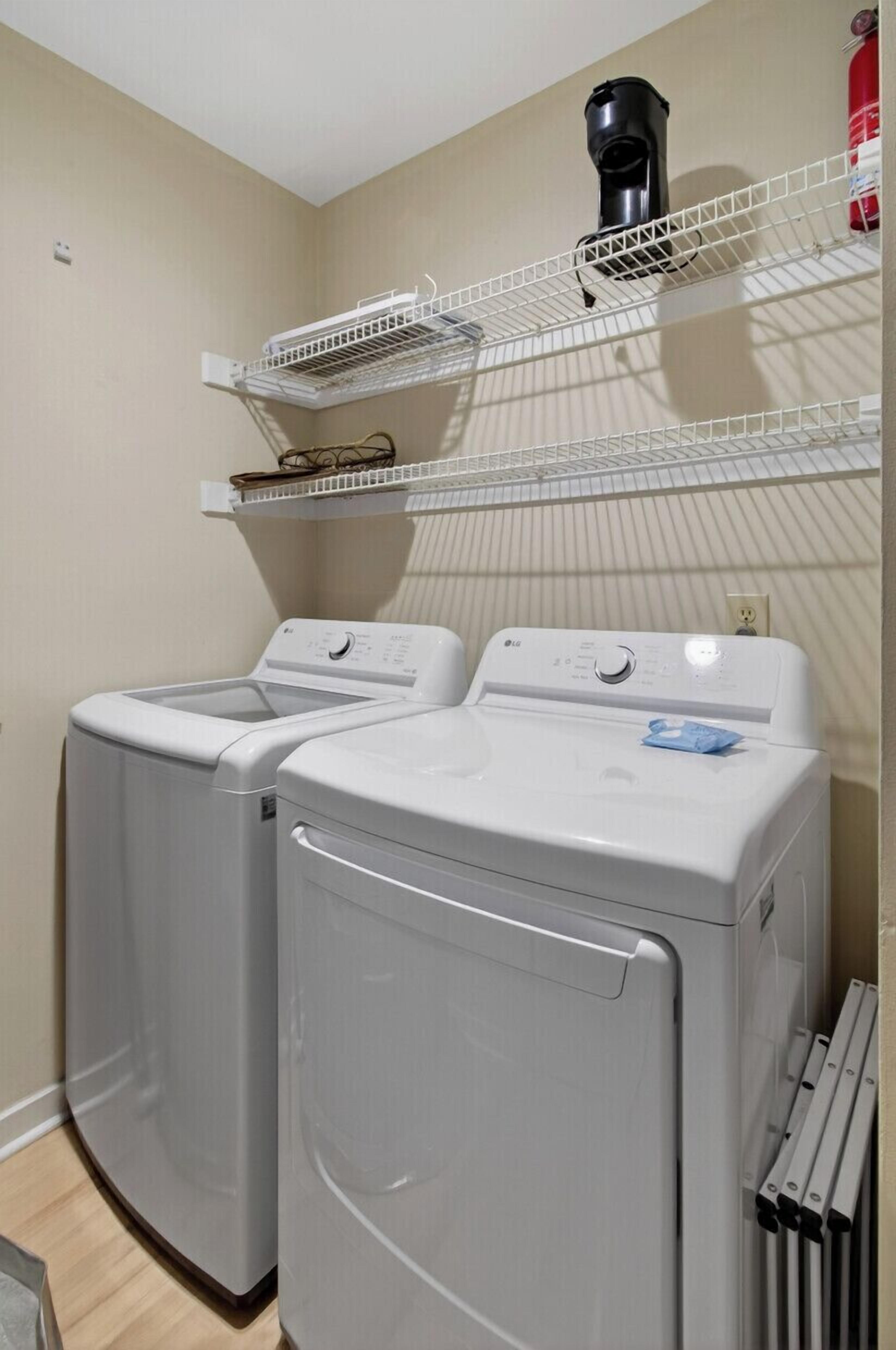 A laundry area with two front-loading washing machines and a drying rack.