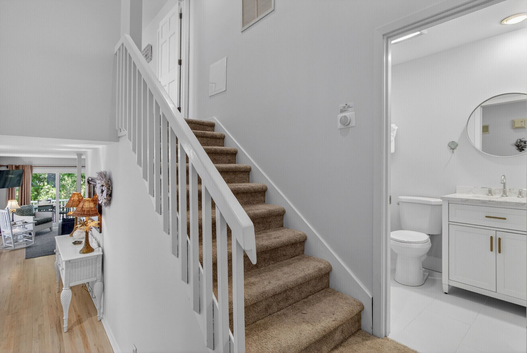 A staircase with white railings leading to a bathroom with a toilet and a vanity.