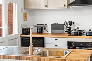 A modern kitchen with stainless steel appliances, a wooden countertop, and a black range hood. - Edison House 2BR Stafford, Sleeps 4 with Parking (Stafford)