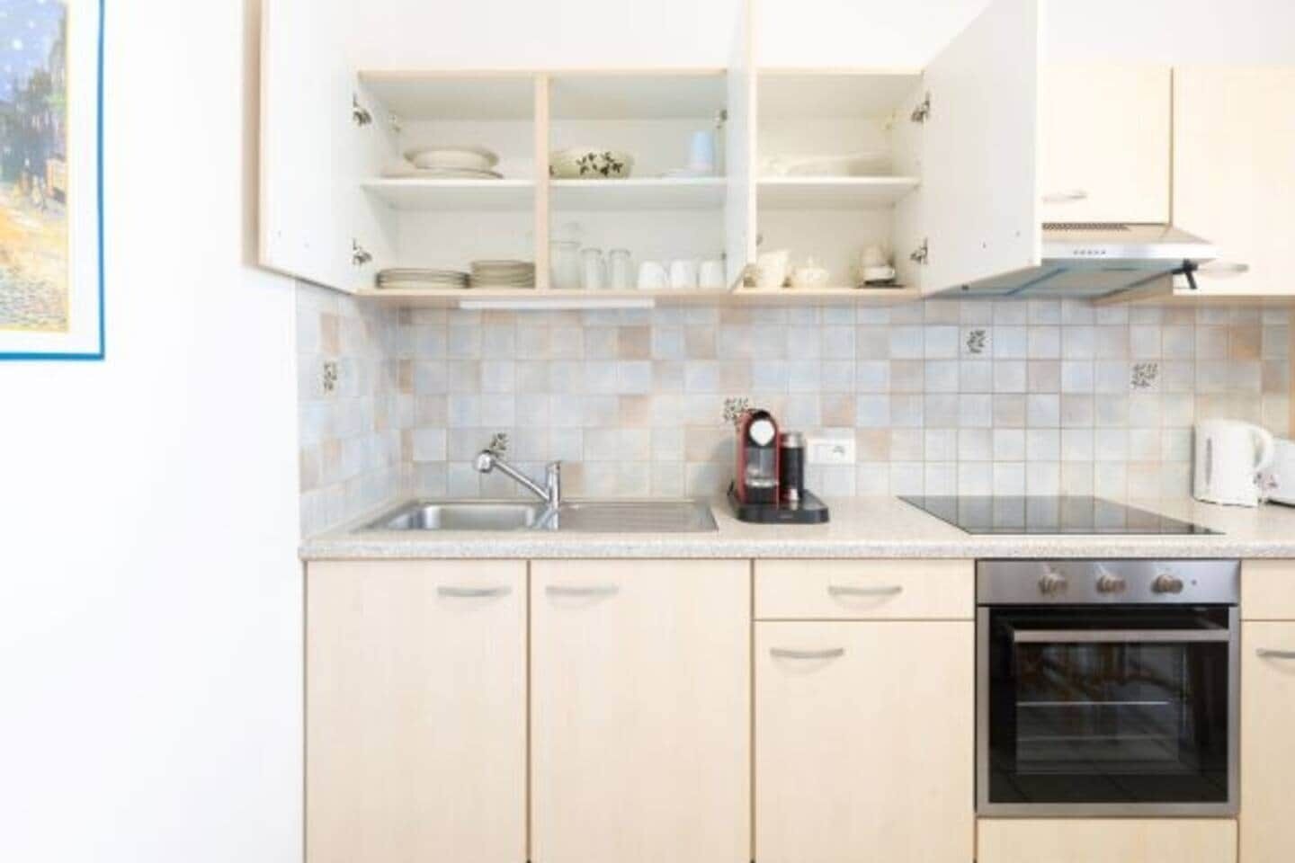 A kitchen with a sink, a coffee maker, and a stove.