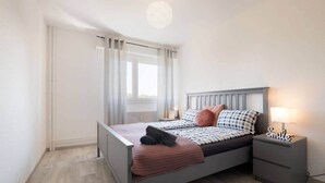 Une chambre à coucher bien rangée, avec un lit, des tables de chevet et une petite table de nuit.
