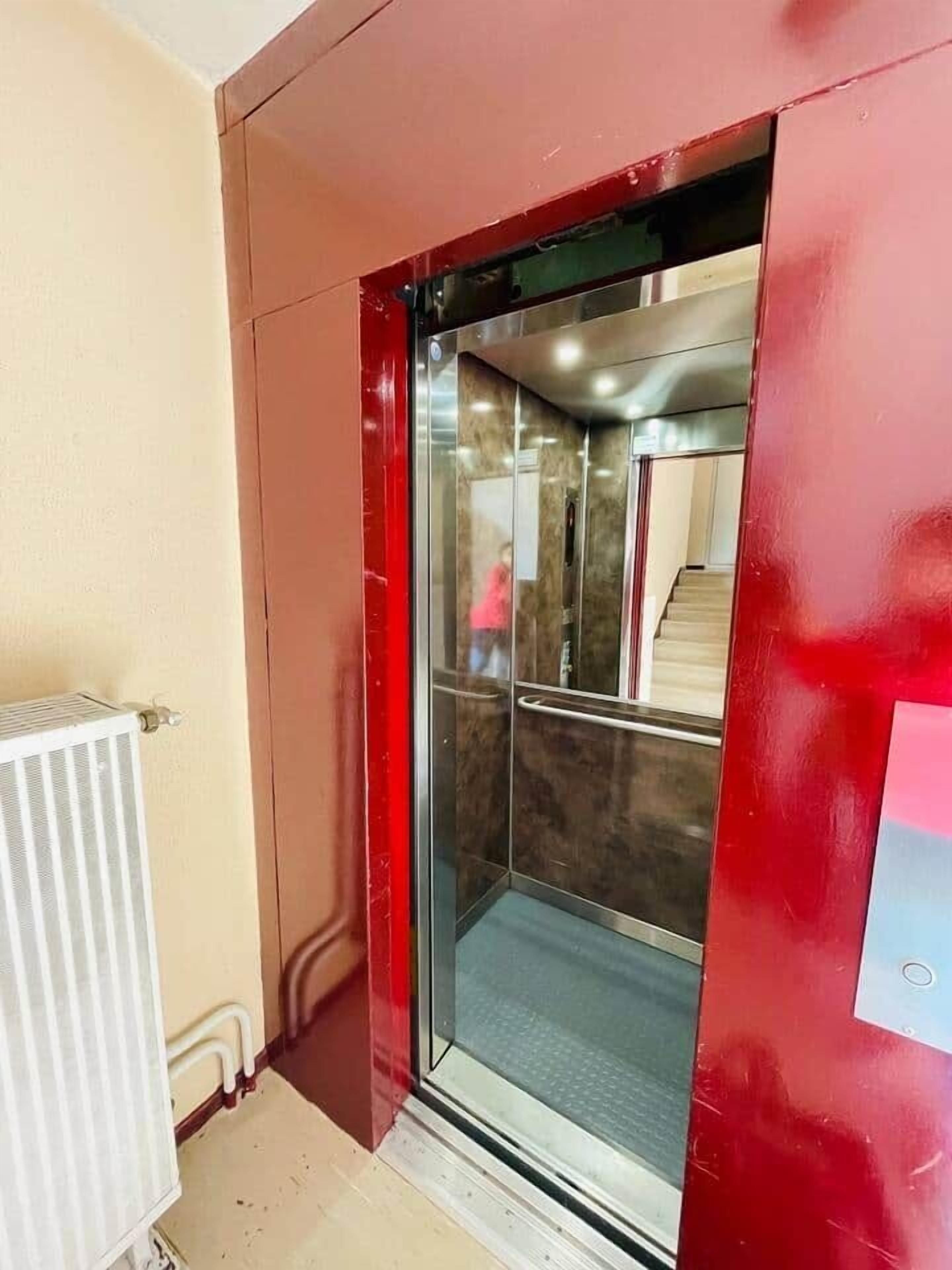 Een lift met een metalen interieur en een rode buitenwand.