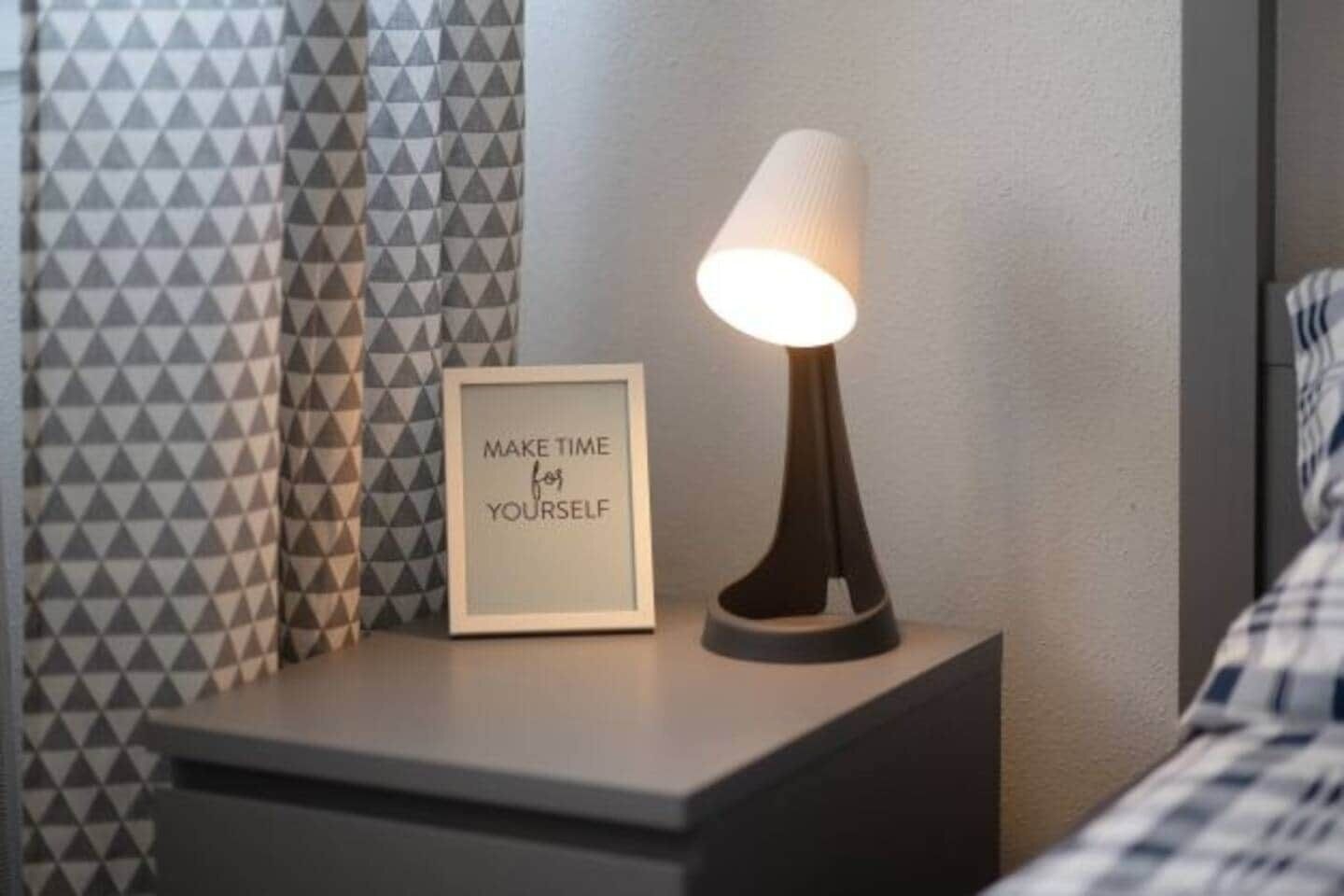 Une table de chevet avec un cadre contenant une citation inspirante, une lampe et des rideaux à motifs.