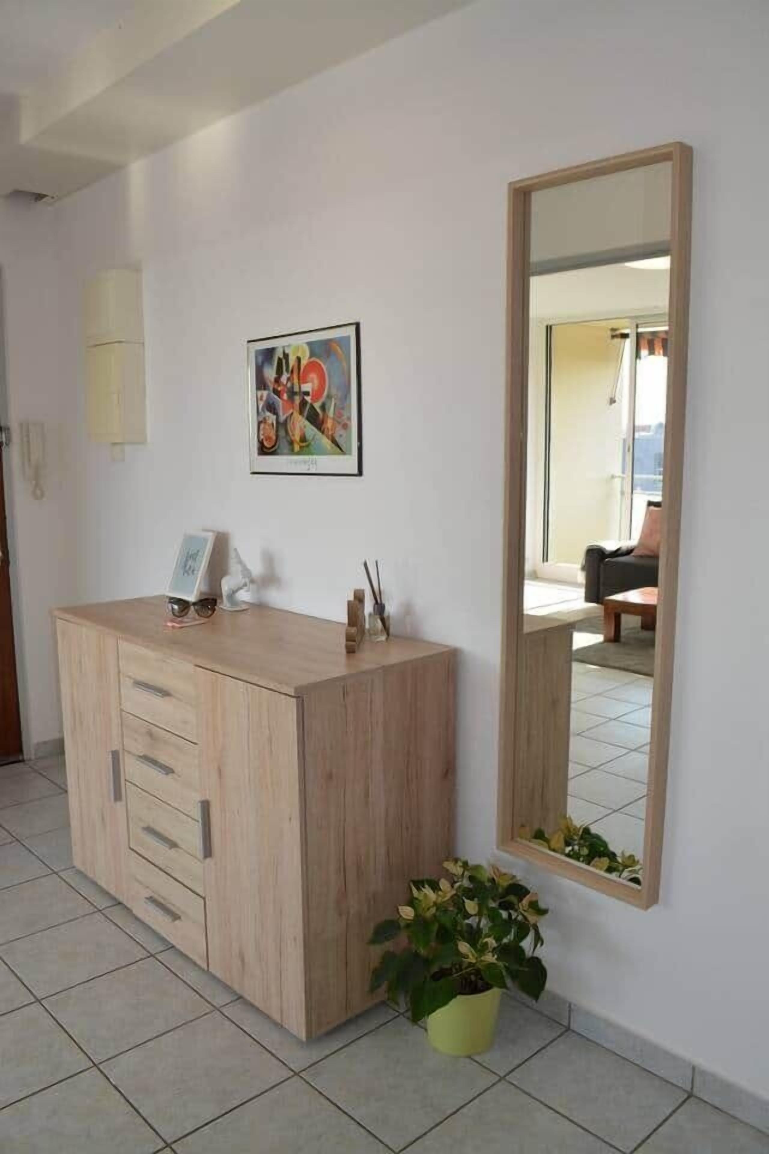 Una habitación con un armario de madera, un cuadro enmarco, un espejo y una planta en maceta.