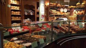 Une vitrine de boulangerie remplie de diverses pâtisseries et une personne derrière le comptoir.