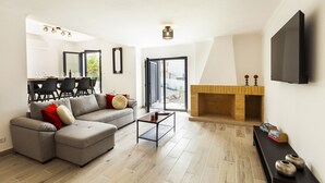 Ein modernes Wohnzimmer mit einer Eckcouch, einem Couchtisch, einem Kamin und einem Essbereich mit Stühlen und Tisch.