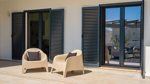 Eine Terrasse mit zwei Stühlen und einer Schiebetür.