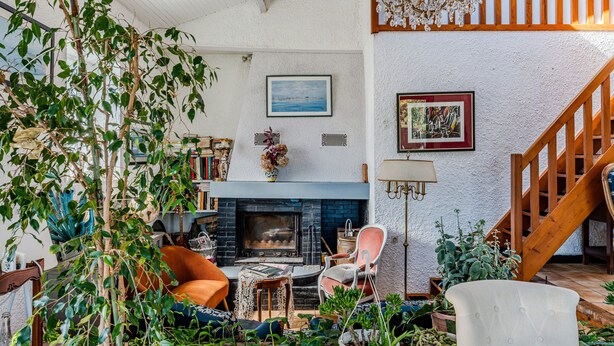 Una sala de estar acogedora con chimenea, asientos cómodos y una escalera que sube a un nivel superior.