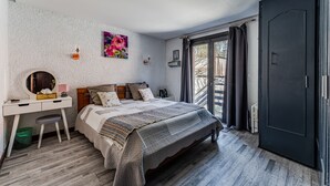 Un dormitorio con cama, escritorio, silla, ventana y puerta.