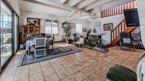 Un salón amplio con comedor, una escalera y un ventanal grande.
