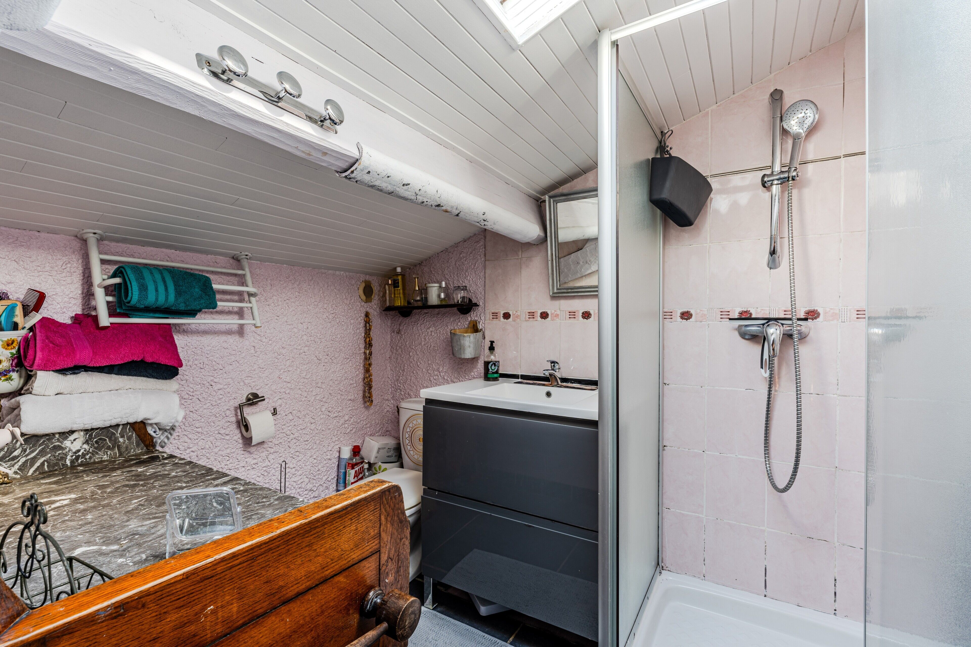 A bathroom with a shower, toilet, sink, and a wooden bed.