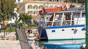 A waterfront scene with a boat docked near a stone wall and buildings in the background. - Josephine House - Four Bedroom Villa, Sleeps 8 (Kalami)