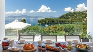 A table set for breakfast with a scenic view of a coastal landscape. - Josephine House - Four Bedroom Villa, Sleeps 8 (Kalami)