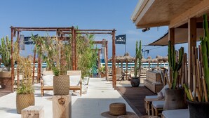 An outdoor seating area with wooden furniture, potted plants, and a bamboo structure. - Trullo Terra Dolce - Four Bedroom Villa, Sleeps 8 (Ostuni)