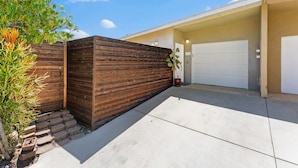 Eine Garage mit Wohnhof, Holzlattenzaun und einem Blumentopf.