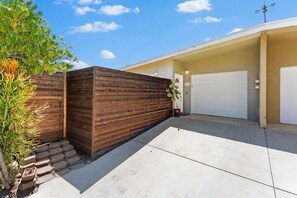 Eine Garage mit Wohnhof, Holzlattenzaun und einem Blumentopf.