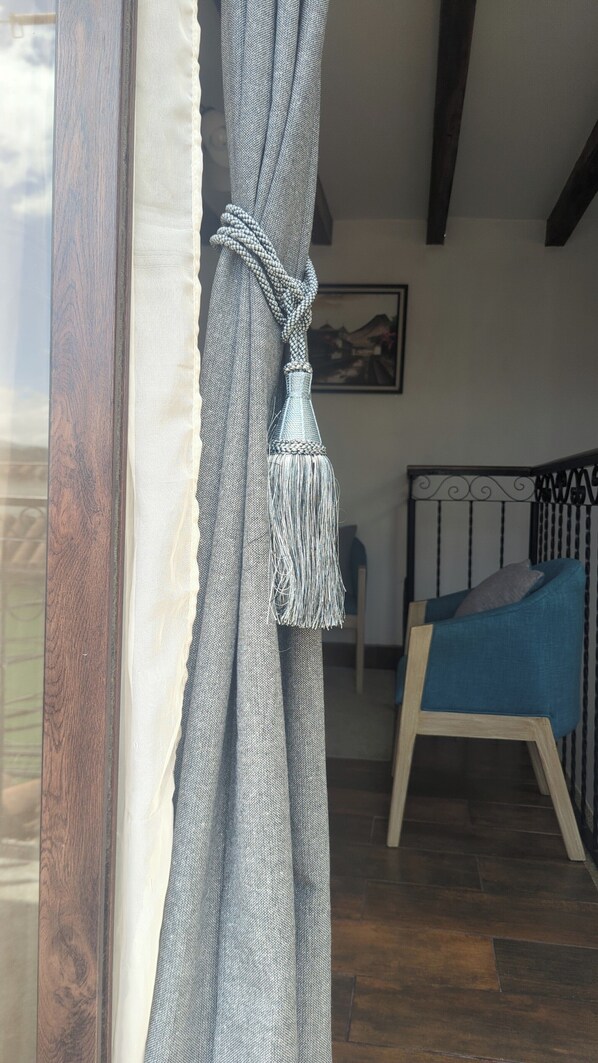 Ein Zimmer mit einem Bett, einem Sessel und einem Fenster mit Vorhängen.