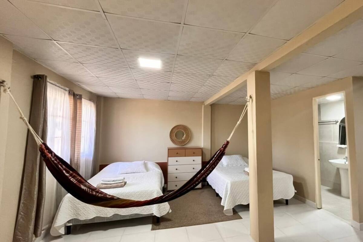A bedroom with two beds, a hammock, a dresser, a sink, and a mirror.