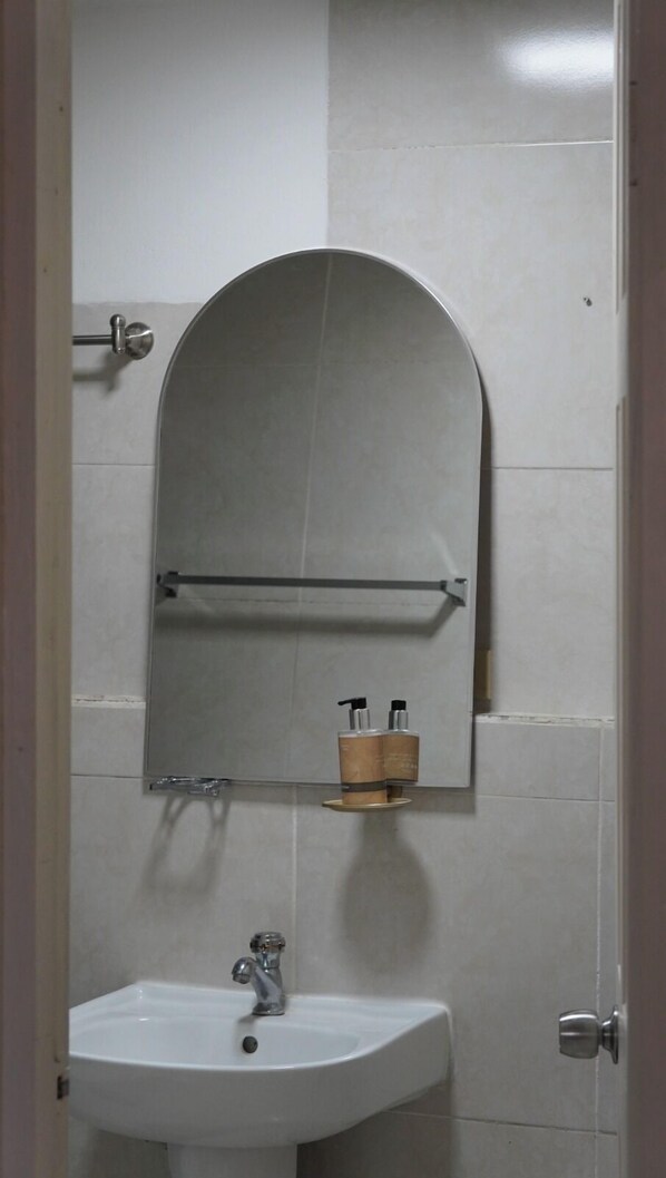 Une salle de bain avec un lavabo blanc, un miroir et un porte-serviettes.