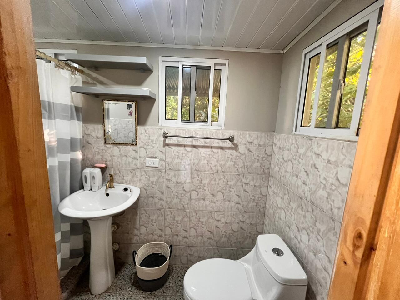Baño con lavamanos pedestal, inodoro y ventana.
