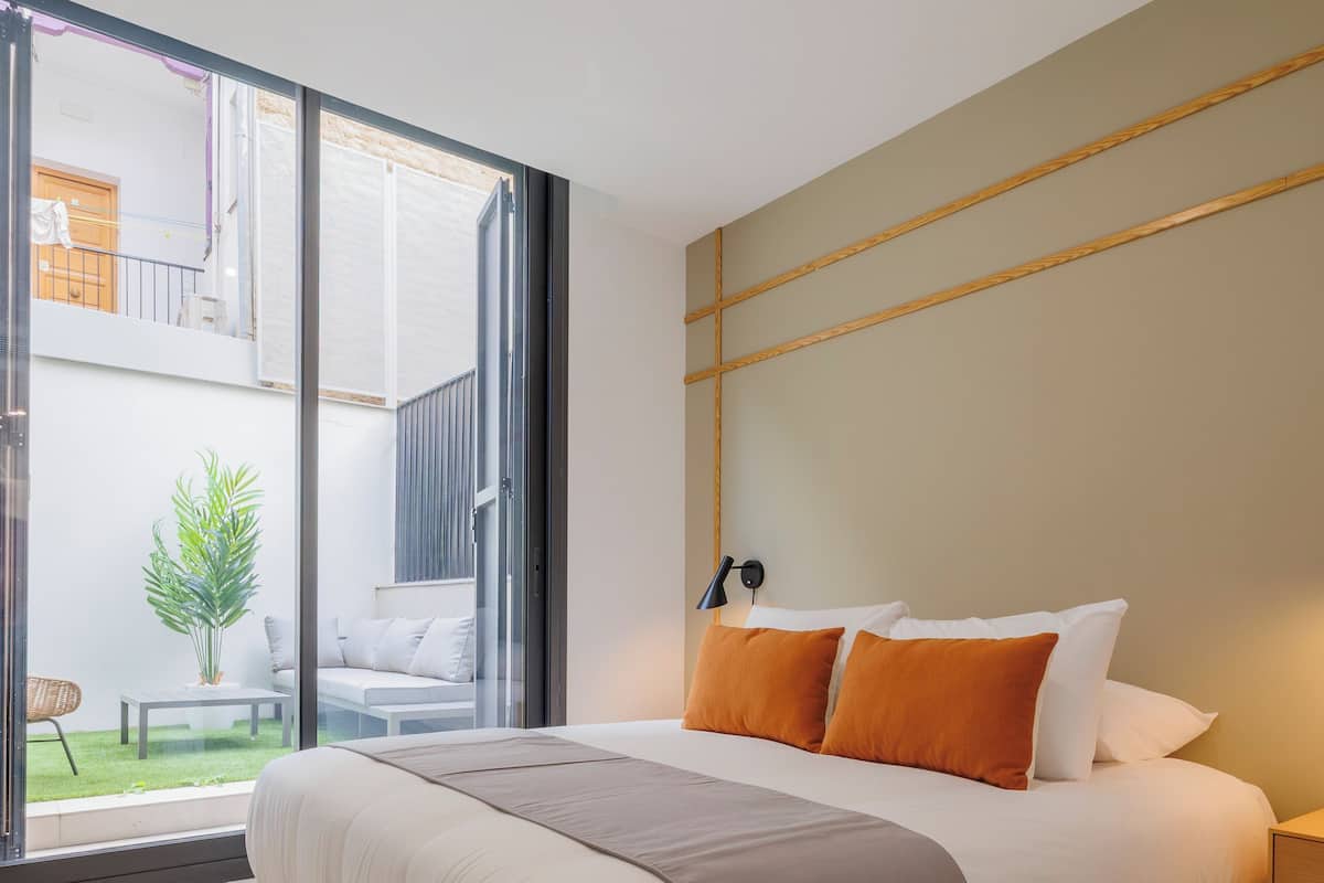 Camera moderna con un letto grande, vista sulla zona esterna e pavimento in legno.