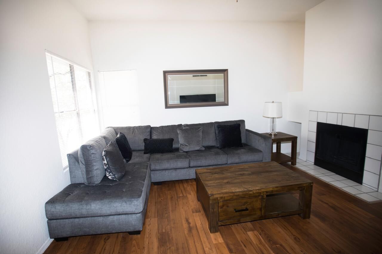 A living room with a grey sectional sofa, a wooden coffee table, a fireplace, and a mirror on the wall.