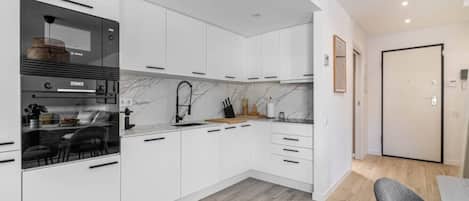 Eine moderne Küche mit weißen Schränken, einem eingebauten Backofen und einem Essbereich mit Tisch und Stühlen.