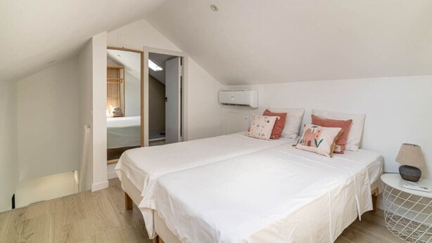 Een slaapkamer met een groot bed, een nachtkastje met een lamp en een airconditioning aan de muur.