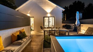 Een modern huis met een zwembad, een terras en een barbecueplek.