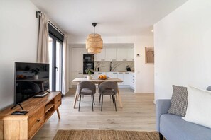 Een moderne woonkamer met een flatscreen televisie, een houten salontafel en een grijze bank.