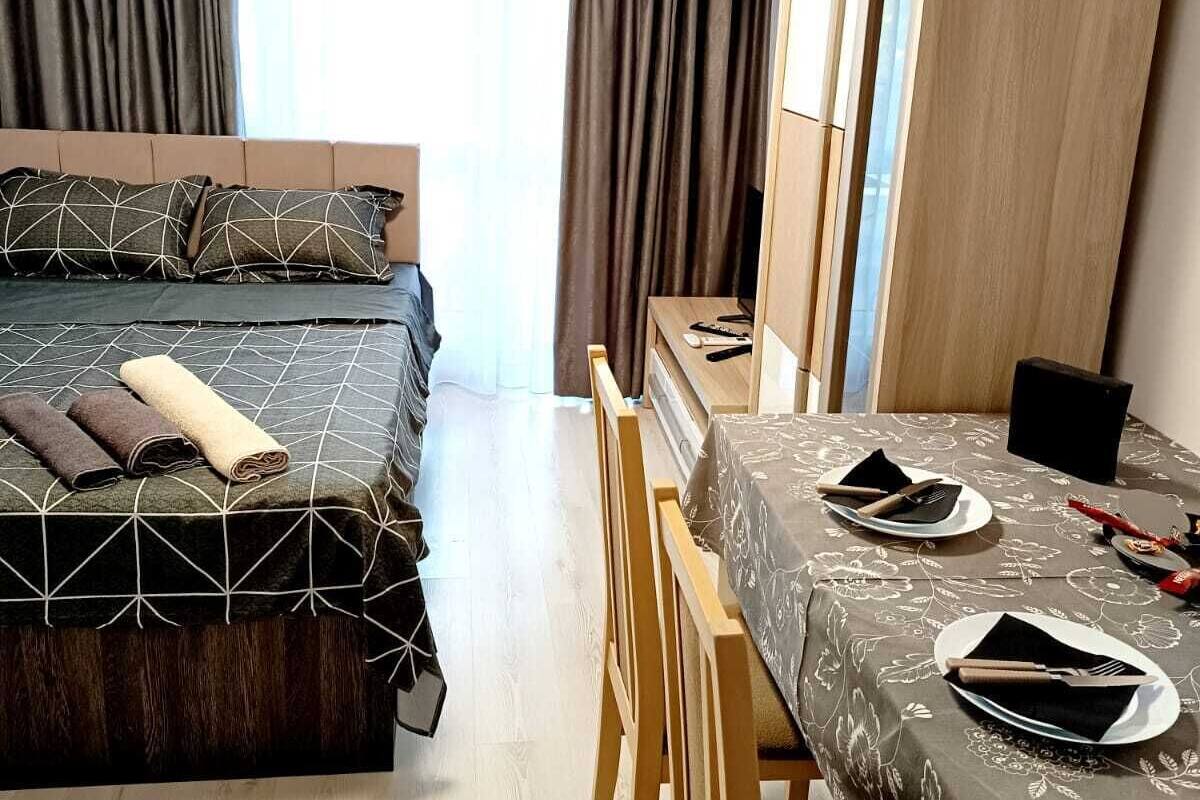 A hotel room with a bed, a dining table set for two, and a wardrobe.
