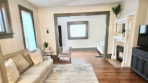 Una sala de estar con sofá, mesa de centro, alfombra, chimenea y televisor.
