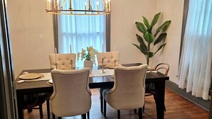 Un comedor con piso de madera, una araña y una planta en maceta.