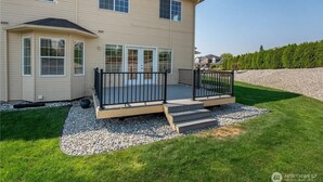 Ein zweigeschossiges Haus mit einer Terrasse, einer überdachten Veranda und einem angelegten Garten.