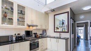 Une cuisine moderne avec des meubles en bois clair, une cuisinière en acier inoxydable et une grande fenêtre.