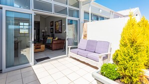 Une maison moderne avec une porte vitrée donnant sur un espace de vie comprenant un canapé et une table à manger.