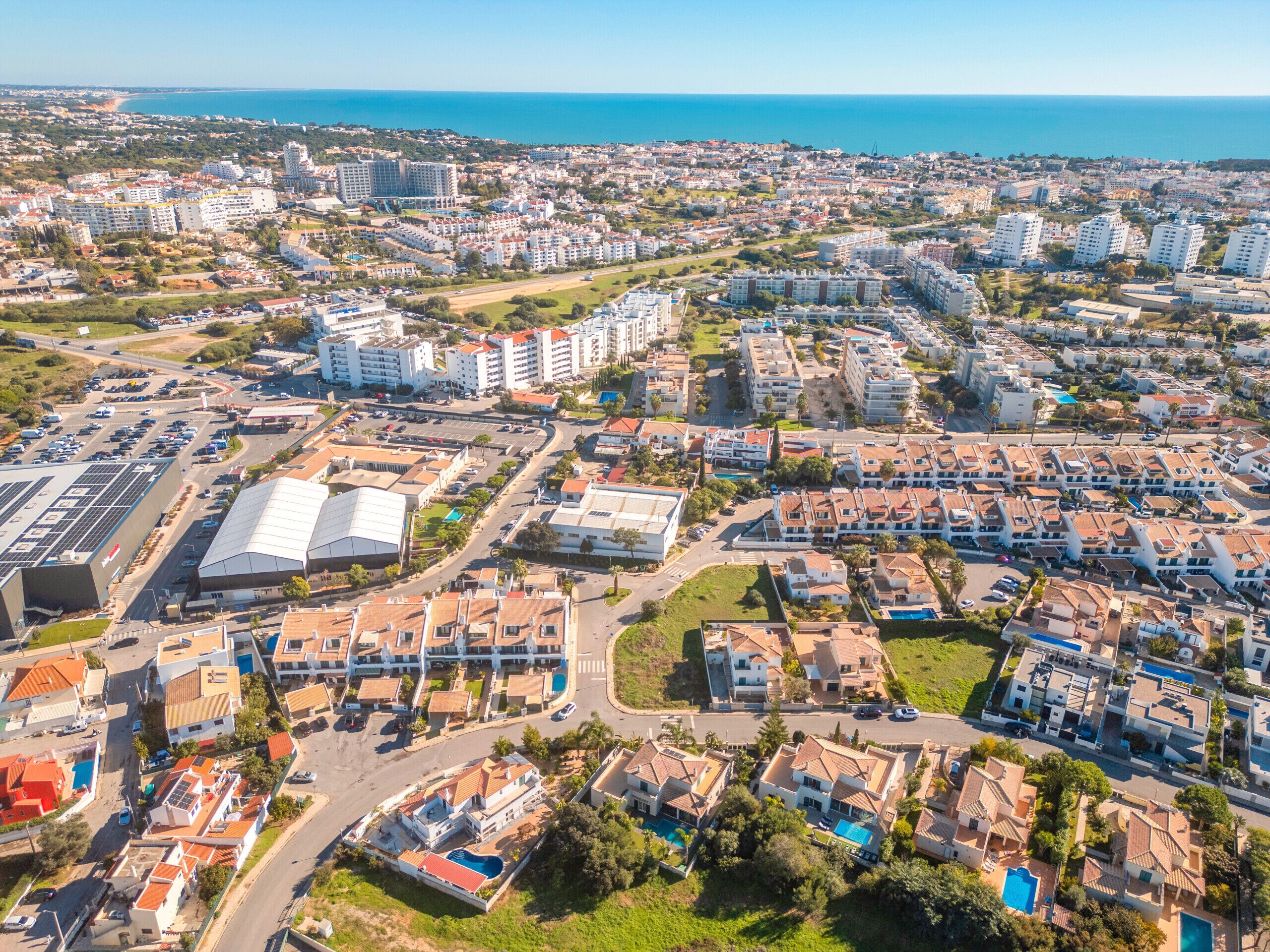 Paisatge urbà costaner amb edificis residencials, un gran edifici comercial i una vista clara del mar.