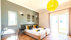 A hotel room with two beds, a desk, and a chair. There are two framed pictures on the wall, and a large window with curtains. - Villa w/ Heatable Pool and BBQ in Albufeira (Albufeira)