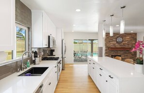 A modern kitchen with white cabinetry, a stainless steel refrigerator, and a built-in gas stove. - Spacious 6-bedroom house with fitness room and AC in charming Buena Park (Buena Park)